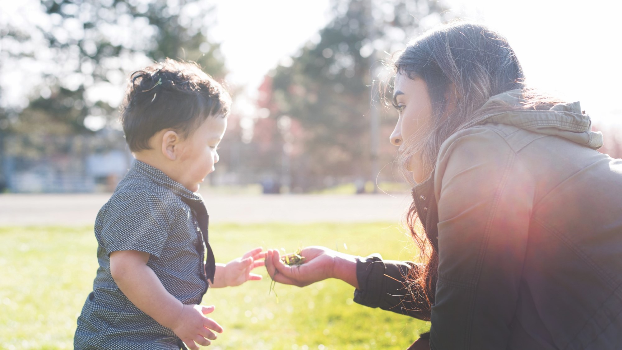 Caregiver interacting with a child outside on a sunny day