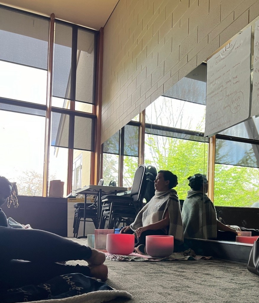 A person sits cross-legged on the floor in front of a mirrored wall.