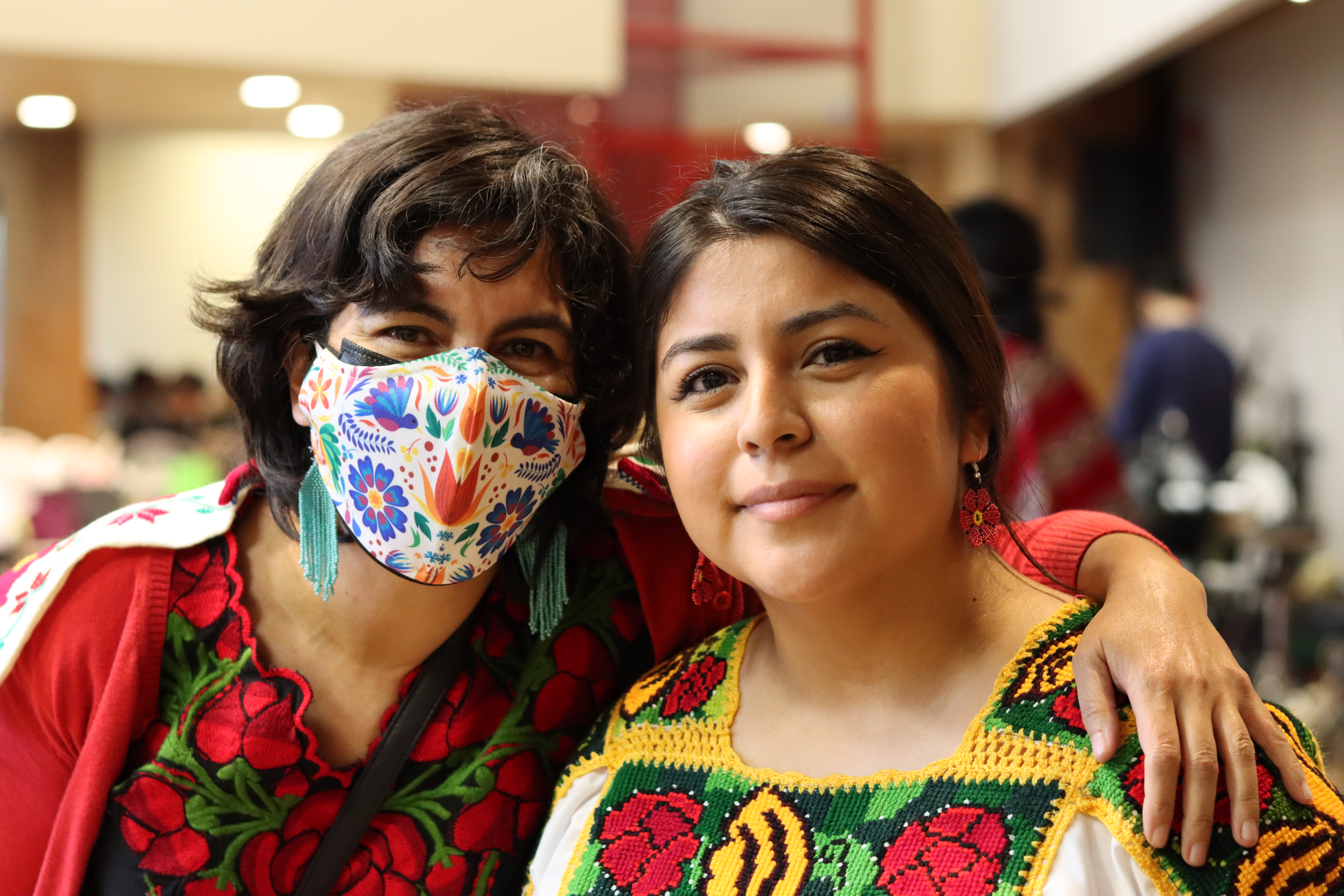 Two faces, one with a mask, looking into a camera.