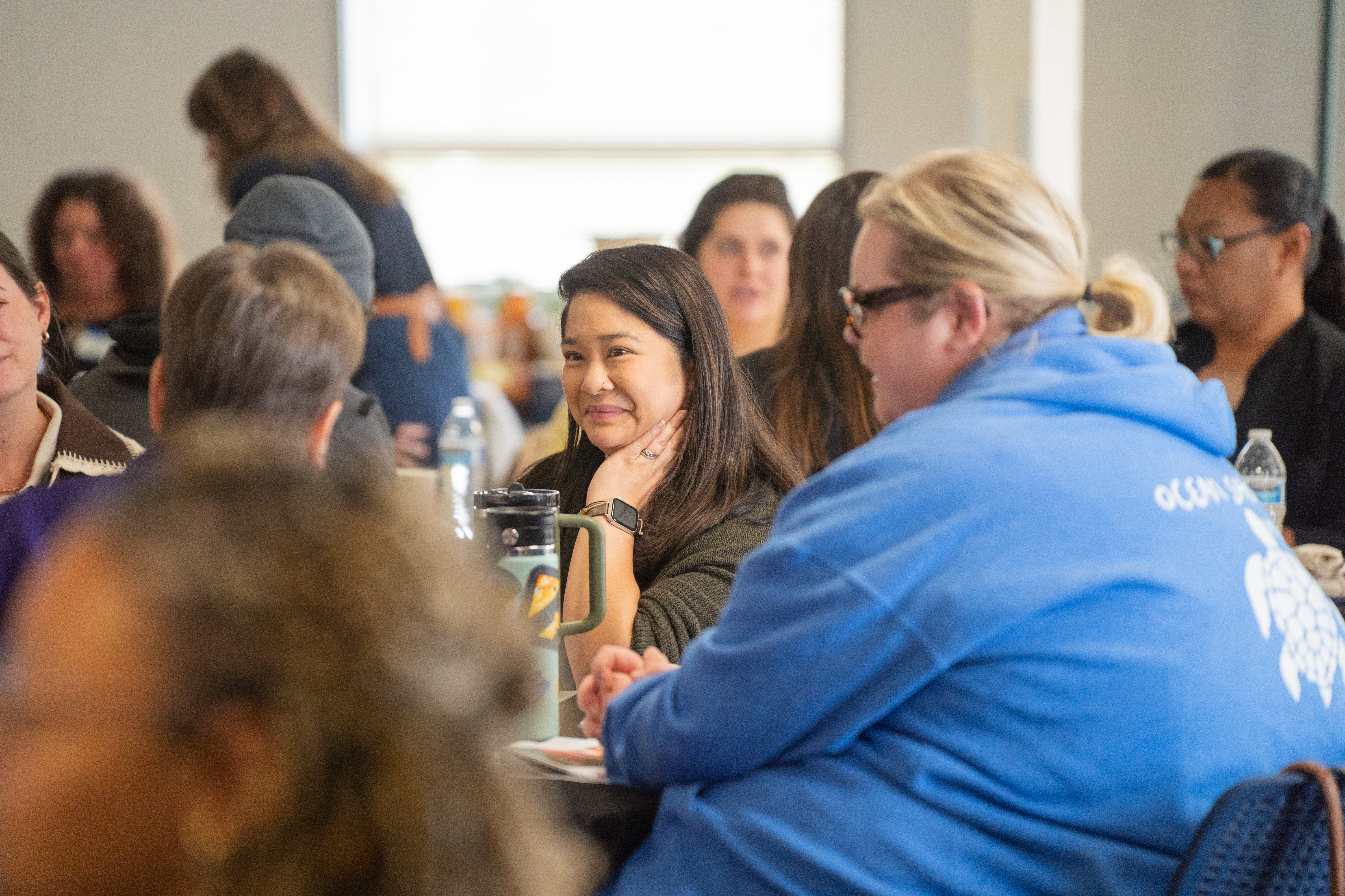Community member smiling and listening in a small group conversation.